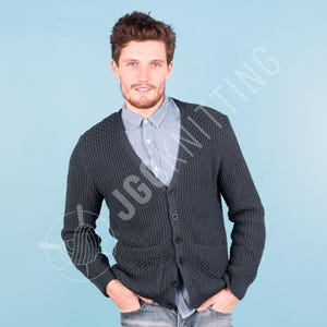 Puede incluir: Un cárdigan gris carbón oscuro con cuello en V, textura de punto grueso, mangas largas y cierre frontal con cinco botones visibles. La prenda incluye dos bolsillos delanteros y se lleva sobre una camisa de cuello abotonado en color azul claro.