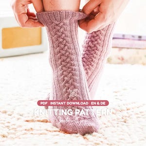 May include: A pair of dusty rose knitted socks featuring a vertical cable knit pattern running down the center. The image includes text that reads PDF INSTANT DOWNLOAD EN & DE KNITTING PATTERN Create with joy in a white and maroon graphic overlay.