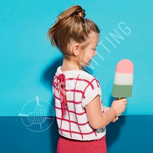 May include: A white knitted short-sleeve top featuring a red grid pattern and a back tie closure. The garment is worn with a solid red knitted bottom piece. The top has a round neckline and a textured knit construction with visible yarn stitches.