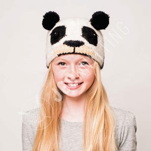 May include: A knitted panda hat with black and white details. The hat features black pom-poms for ears and a panda face design. The hat is made of a soft, textured material and is designed to fit comfortably.