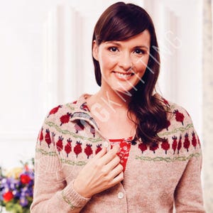 May include: A beige cardigan featuring a red and green pattern. The cardigan has a button-up front and a patterned design around the neckline and sleeves. The person in the image is wearing a red floral top underneath.