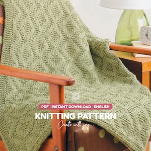 May include: A sage green knitted blanket featuring a textured diamond pattern. The image includes text that reads: PDF INSTANT DOWNLOAD ENGLISH KNITTING PATTERN Create with joy. The blanket is draped over a wooden chair with brown upholstery.