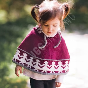May include: A knitted burgundy hooded cape with a white and gray border, worn by a young child. The cape features a repeating pattern of white figures along the bottom edge. The hood has a gray drawstring.