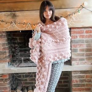 以下が含まれることがあります： テクスチャードデザインとポンポンディテールが施された、明るいピンク色のニットショール。 ショールは肩にかけられ、長いフリンジエッジが特徴です。 この衣服は柔らかく暖かい素材で作られており、肌寒い季節に最適です。