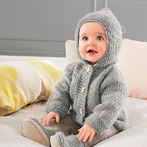 May include: A light gray knitted hooded cardigan featuring a garter stitch texture, long sleeves, and three round buttons down the front. The garment is paired with matching light gray knitted pants and soft, light-colored booties.