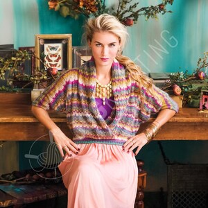 May include: A multi-colored knit sweater with a wide shawl collar featuring horizontal stripes in shades of yellow, pink, purple, and grey, worn over a solid purple top and a long, flowing light peach-colored skirt with a gold beaded necklace.