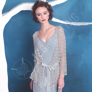 May include: A light grey, open-front lace cardigan with three-quarter length sleeves and a delicate, intricate knit pattern. The garment features a matching ribbon tie at the waist and scalloped edges, worn over a solid light grey slip dress.