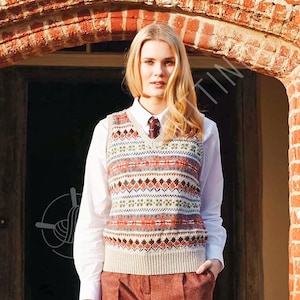 Op de afbeelding: Een gebreide fair isle patroon vest in beige, oranje, groen en bruin. Het vest wordt gedragen over een wit overhemd en een stropdas met patroon. De stijl is klassiek en preppy.