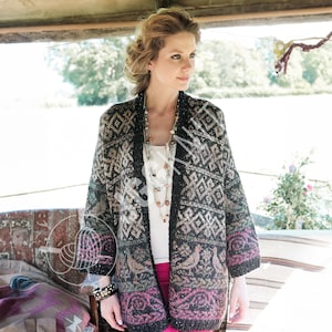 May include: A patterned cardigan in shades of black, gray, and beige. The open-front sweater features geometric and bird motifs, with a pink border at the hem and sleeves. The cardigan is worn over a white top.
