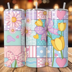 Może przedstawiać: Trzy izolowane kubki z kwiatowymi i kokardkowymi wzorami. Każdy kubek ma wzór patchworkowy z stokrotkami, tulipanami, sercami i kokardkami w pastelowych kolorach. Kubki mają słomkę i pokrywkę.