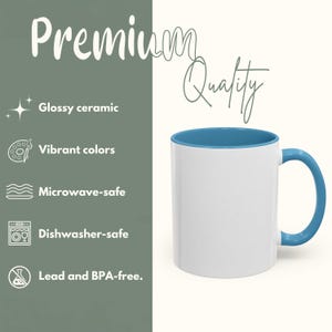 Op de afbeelding: Witte keramische mok met een blauwe binnenkant en handvat. De mok heeft de woorden "Premium Quality" in een scriptlettertype. De afbeelding vermeldt ook dat de mok glanzend is, levendige kleuren heeft, magnetron- en vaatwasserbestendig is en lood- en BPA-vrij.