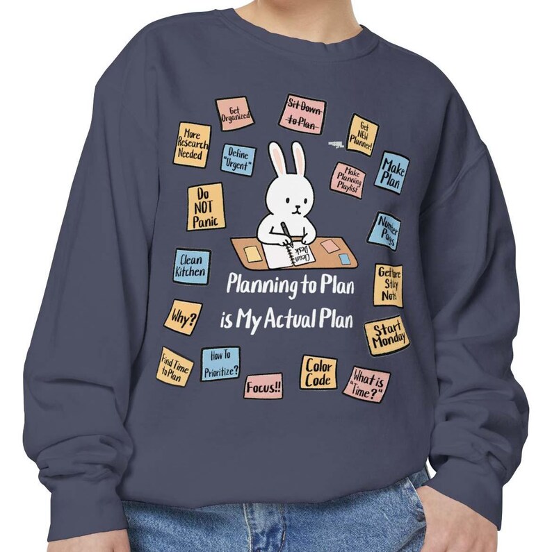 May include: Navy blue sweatshirt featuring a cartoon bunny at a desk with the text "Planning to Plan is My Actual Plan." Surrounding the bunny are sticky notes with phrases like "Make Plan" and "Do Not Panic."