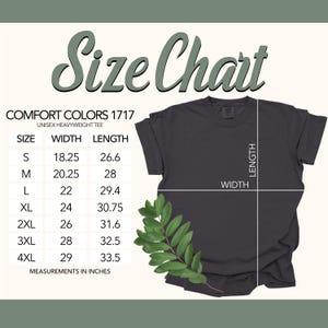 May include: A dark gray Comfort Colors unisex heavyweight tee shirt with a size chart. The chart lists sizes S to 4XL, with width and length measurements in inches. A sprig of green leaves is in the lower right corner.