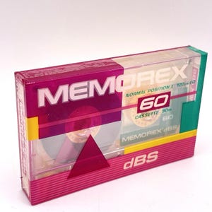 May include: A Memorex 60 cassette tape in its original packaging. The packaging is a clear plastic box with a pink and green design. The tape is labeled "MEMOREX" and "60".