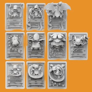 May include: Nine 3D printed Pokemon trading cards featuring different Pokemon characters. The cards are white and have a raised design. The Pokemon characters include Bulbasaur, Charmander, Squirtle, Venusaur, Charmeleon, Blastoise, Pikachu, Charizard, and a Pokemon with a flower on its head.