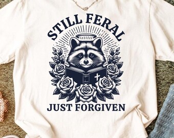Still Feral gerade vergeben Shirt | Lustiges christliches Waschbär-Shirt | Mutiger Glaube | Western Wild Believer Tshirt Motiv | Frecher verziehener Humor