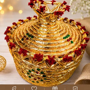 May include: A gold-colored, woven basket with a lid, adorned with red floral accents. The basket has a unique, layered design and is suitable for gifting. The image also includes icons that say "Handcrafted with care", "Unique design", "Perfect for gifting", and "Durable & quality made".