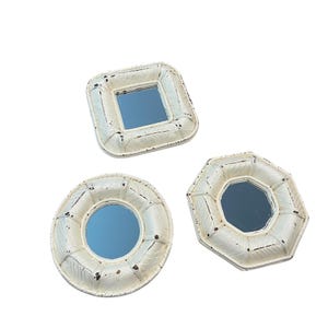 May include: Three decorative mirrors in different shapes: square, round, and octagonal. Each mirror has a distressed white frame with a textured design and a reflective blue surface. The mirrors are ideal for wall decor.