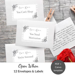 Könnte beinhalten: Drei weiße Umschläge mit Etiketten mit Blumenmotiven und den Texten Open When You Can't Sleep, Open When You Need Motivation und Open When You're Stressed. Ein handgeschriebener Zettel, zwei hölzerne Wäscheklammern und rote Rosen sind zu sehen.