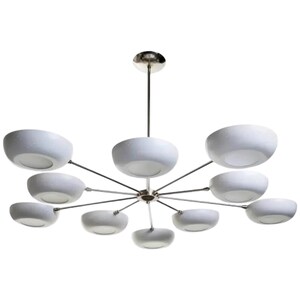May include: A modern chandelier with a polished chrome finish and ten white, bowl-shaped shades. The shades are evenly spaced around a central hub, creating a starburst design. The fixture is suspended from a single chrome rod.
