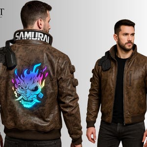 May include: Brown bomber jacket with a Samurai collar and a vibrant, color-shifting Oni mask graphic on the back. The jacket features a zip-up front, ribbed cuffs, and multiple decorative accents. The word "SAMURAI" is printed on the collar.