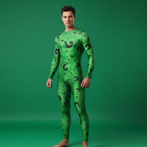 Könnte beinhalten: Grüner Ganzkörperanzug mit schwarzen Fragezeichen. Der langärmlige Overall bedeckt den gesamten Körper, einschließlich Beine und Arme. Der Anzug besteht aus einem glänzenden, dehnbaren Material.
