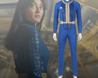 May include: A blue jumpsuit with tan accents, a zipper, and a belt is displayed on a mannequin. The jumpsuit has long sleeves and is form-fitting. The word "DOT" is visible in the upper left corner of the image. A person is visible in the background.