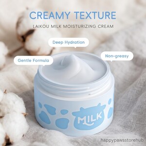 K&ouml;nnte beinhalten: Ein hellblaues Glas LAIKOU Milk Moisturizing Cream mit cremiger Textur, mit einem Kuhdesign und dem Wort "MILK". Das Bild enth&auml;lt Baumwollbl&uuml;ten und Text, der "Tiefe Hydratation" und "Nicht fettend" angibt.