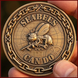 Op de afbeelding: Een bronzen munt met een gedetailleerd ontwerp. De munt toont een bij die gereedschap vasthoudt, met de woorden "SEABEES CAN DO" eromheen. De munt heeft een kettingrand en gereedschapsmotieven.