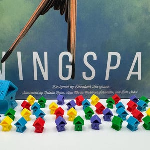 May include: A blue game piece with the text "1st Player" and a birdhouse design. There are 25 colorful birdhouse game pieces in various colors, including yellow, red, green, and purple.