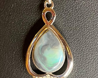 May include: Silver pendant necklace featuring a teardrop-shaped opal stone with swirling blue and green hues. The pendant is encased in a silver frame with a diamond-like accent at the bottom. The necklace chain is a delicate silver.