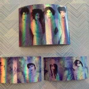 Op de afbeelding: Een set van vijf iriserende holografische stickers met een band van vijf personen. De stickers zijn rechthoekig en hebben een regenboog effect.