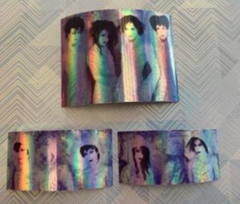 Op de afbeelding: Een set van vijf iriserende holografische stickers met een band van vijf personen. De stickers zijn rechthoekig en hebben een regenboog effect.