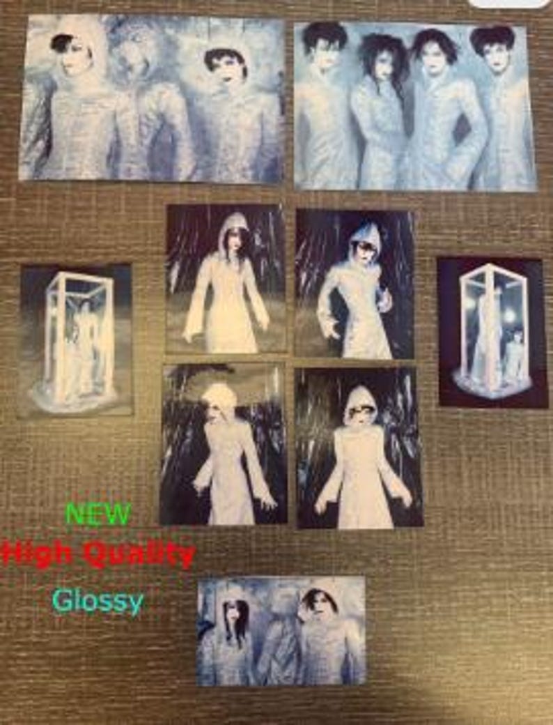 Op de afbeelding: Set van acht glanzende fotokaarten met een band in verschillende poses. De bandleden dragen witte gewaden met kap en staan in een besneeuwde of ijzige omgeving. De foto's zijn van hoge kwaliteit en hebben een vintage uitstraling.