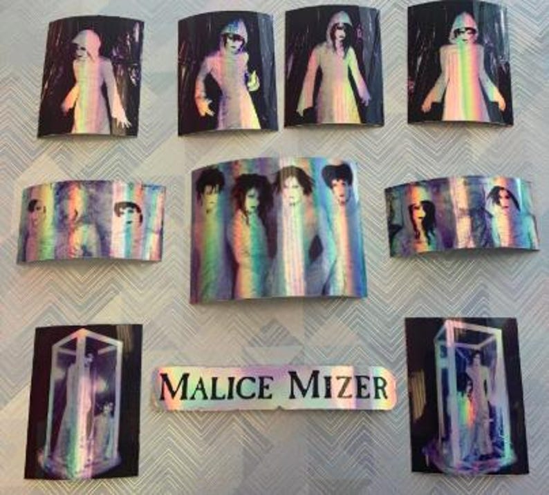 Op de afbeelding: Een verzameling van negen holografische stickers met de band Malice Mizer. De stickers zijn rechthoekig en tonen afbeeldingen van de bandleden in verschillende poses. De stickers zijn iriserend en hebben een regenboog-effect.