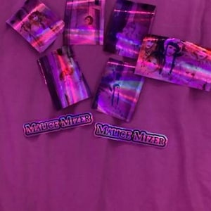 May include: A collection of holographic stickers featuring images of people and the text "Malice Mizier".