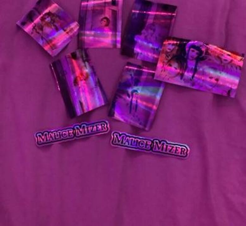May include: A collection of holographic stickers featuring images of people and the text "Malice Mizier".