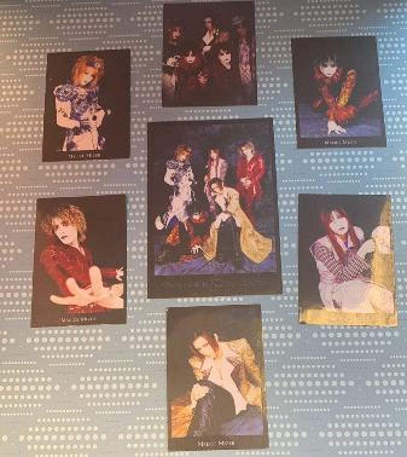 May include: A set of seven black and white photos of a Japanese rock band. The photos feature the band members in various poses and outfits. The band's name is written in Japanese on the bottom of each photo.