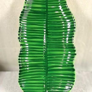 May include: A glossy, green decorative leaf-shaped platter. The platter has a detailed ribbed texture and is supported by a black stand. The vibrant green color and unique shape make it a striking decorative piece.