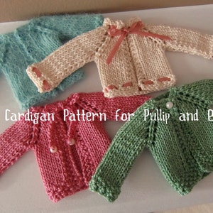 May include: Four knitted cardigans in different colors: teal, cream, pink, and green. The cardigans are laid out on a white surface. The text "Easy Cardigan Pattern for Pullip and Blythe" is written below the cardigans.