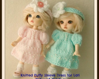 May include: Two dolls wearing knitted puffy sleeve dresses. The doll on the left is wearing a pink dress with white pearl accents and a white flower headband. The doll on the right is wearing a turquoise dress with white pearl accents and a white flower headband. The caption reads "Knitted Puffy Sleeve Dress for Lati Yellow & Pukifee".
