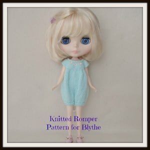 Op de afbeelding: Een breipatroon voor een romper voor Blythe-poppen. De romper is lichtblauw met een witte rand en een rij kleine witte bloemetjes op het bovenstuk. De pop draagt de romper en heeft blond haar en blauwe ogen.
