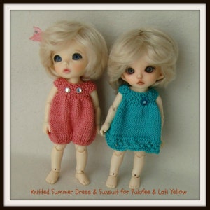May include: Two dolls wearing knitted summer dresses. The doll on the left is wearing a pink dress and the doll on the right is wearing a turquoise dress. Both dolls have blonde hair and blue eyes.