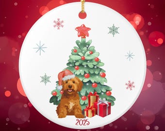 May include: Round Christmas ornament featuring a brown dog wearing a Santa hat, sitting in front of a decorated Christmas tree. The tree has red ornaments and a star on top. The year "2025" is printed at the bottom.