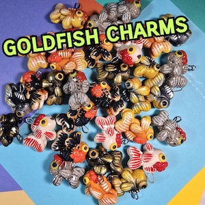 May include: A collection of colorful, handmade goldfish charms. Each charm is made of polymer clay and features a unique design. The charms are perfect for adding a touch of whimsy to jewelry, keychains, or other crafts.