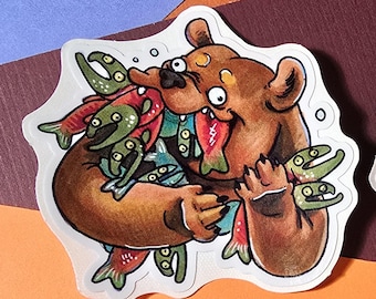 Puede incluir: Un oso marrón con una amplia sonrisa sostiene un montón de salmones en sus patas. Los salmones son rojos y naranjas con manchas verdes y blancas. El oso está sobre un fondo blanco.