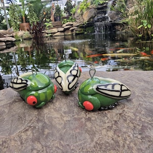 Puede incluir: Un juego de tres tazas de cerámica con un acabado mate moteado. Las tazas son de color crema, gris claro y gris oscuro. Cada taza tiene un diseño simple y minimalista y un asa redondeada.