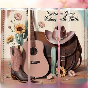 May include: A set of three pink and brown tumblers with a western theme. The tumblers feature a guitar, cowboy hat, boots, and cactus. The text on the tumblers reads "Rooted in Grace. Riding with Faith."