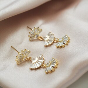 vintage style geometric fan shaped earrings laying flat on a light pink satin cloth