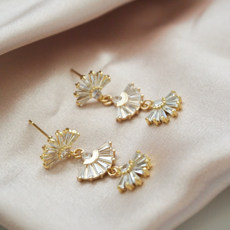 vintage style geometric fan shaped earrings laying flat on a light pink satin cloth
